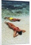 1990s Couple Sunbathing In Shallow Water At The Ocean's Edge by Anonymous