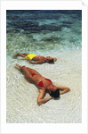 1990s Couple Sunbathing In Shallow Water At The Ocean's Edge by Anonymous