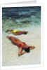 1990s Couple Sunbathing In Shallow Water At The Ocean's Edge by Anonymous