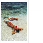 1990s Couple Sunbathing In Shallow Water At The Ocean's Edge by Anonymous