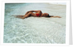 1990s Woman In Red Bikini Lying In Shallow Water On The Beach by Anonymous