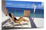 1990s Woman Wearing Black And Gold Bathing Suit Sunbathing On Patio In Deck Chair by Anonymous