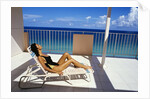 1990s Woman Wearing Black And Gold Bathing Suit Sunbathing On Patio In Deck Chair by Anonymous