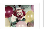 1950s Circus Clown Portrait Smiling Amid Balloons Pointing Up Looking At Camera by Anonymous