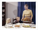1960s Grandmother Presenting Roasted Turkey To Children At Dining Room Table by Anonymous