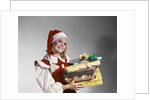 1960s Young Woman In Red And White Santa Helper Costume And Hat Holding Pile Of Wrapped Christmas Presents Studio by Anonymous