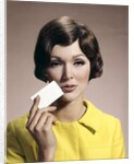 1960s Brunette Woman Holding Blank Business Card To Face Looking At Camera Wearing Yellow Top by Anonymous