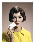 1960s Brunette Woman Holding Blank Business Card To Face Looking At Camera Wearing Yellow Top by Anonymous