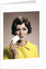 1960s Brunette Woman Holding Blank Business Card To Face Looking At Camera Wearing Yellow Top by Anonymous