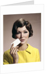1960s Brunette Woman Holding Blank Business Card To Face Looking At Camera Wearing Yellow Top by Anonymous