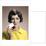 1960s Brunette Woman Holding Blank Business Card To Face Looking At Camera Wearing Yellow Top by Anonymous