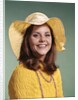 1970s Smiling Young Woman Wearing Yellow Floppy Brim Hat And Blouse With Pink Beads Looking At Camera by Anonymous