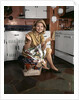 1960s Young Smiling Blond Housewife Sitting On Top Of Laundry Basket Kitchen by Anonymous