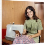 1970s Young Woman Teenager Using A Singer Sewing Machine Looking At Camera by Anonymous