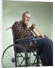 1960 1960s Retro Senior Man Sitting In Wheelchair With Crutches Blanket Wrapped Around Legs by Anonymous