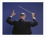 1950s 1960s 1970s View Of Back Of Bald Man Conducting A Symphony Orchestra by Anonymous