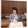 1970s Smiling Woman Bank Teller Handing Cash Over Counter by Anonymous