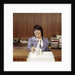1970s Smiling Woman Bank Teller Handing Cash Over Counter by Anonymous