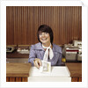1970s Smiling Woman Bank Teller Handing Cash Over Counter by Anonymous