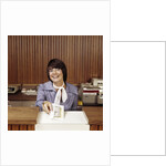 1970s Smiling Woman Bank Teller Handing Cash Over Counter by Anonymous