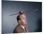 1960s Anxious Nervous Man Looking Up At Arrow Shot Through An Apple Sitting On Top Of His Head by Anonymous