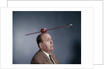 1960s Anxious Nervous Man Looking Up At Arrow Shot Through An Apple Sitting On Top Of His Head by Anonymous