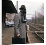 1950s Man Wearing Gas Mask Hat At Commuter Train Station Holding Briefcase Newspaper by Anonymous