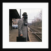 1950s Man Wearing Gas Mask Hat At Commuter Train Station Holding Briefcase Newspaper by Anonymous