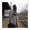 1950s Man Wearing Gas Mask Hat At Commuter Train Station Holding Briefcase Newspaper by Anonymous