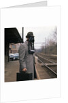 1950s Man Wearing Gas Mask Hat At Commuter Train Station Holding Briefcase Newspaper by Anonymous