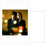 1960s 1970s Young Couple Man Woman Head To Head Dressed In Black Look At Camera Mod Style Serious Expression Blur Lights by Anonymous