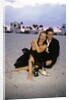 1990s Laughing Couple Man Woman In Formal Wear Sitting Hugging On Beach by Anonymous