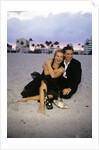 1990s Laughing Couple Man Woman In Formal Wear Sitting Hugging On Beach by Anonymous