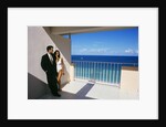 1990s Man In Dark Suit And Tie And Woman In White One Piece Bathing Suit Standing Together On Ocean Side Sun Deck by Anonymous