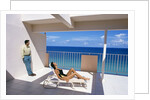 1990s Man And Woman On Sunny Deck Balcony Overlooking The Ocean by Anonymous