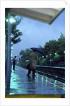 1970s 1980s Anonymous Business Man Holding Umbrella Waiting For A Commuter Train by Corbis