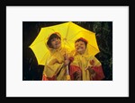 1990s Two Laughing Young Girls Holding A Yellow Umbrella And Wearing Yellow Rain Ponchos by Anonymous