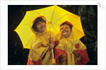 1990s Two Laughing Young Girls Holding A Yellow Umbrella And Wearing Yellow Rain Ponchos by Anonymous