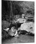 1950s Lazy Fisherman Lying Back On Rock With Hat Pulled Over Eyes Fishing In Creek by Anonymous