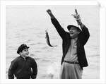 1950s 1960s Boy Son Fishing With Man Father Or Grandfather Holding Up Caught Fish On Line Laughing Having Fun by Anonymous