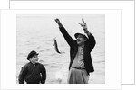 1950s 1960s Boy Son Fishing With Man Father Or Grandfather Holding Up Caught Fish On Line Laughing Having Fun by Anonymous