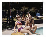 1960s Four People On Patio Couple Man Woman Sitting On Edge Of Swimming Pool by Anonymous