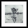 1950s Brunette Bathing Beauty In Polka Dot Bikini Standing In Sand With Hands Behind Head Looking At Camera by Anonymous