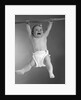 1960s Baby Hanging From Rod With Frightened Expression On Verge Of Tears by Anonymous