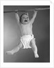 1960s Baby Hanging From Rod With Frightened Expression On Verge Of Tears by Anonymous