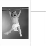 1960s Baby Hanging From Rod With Frightened Expression On Verge Of Tears by Anonymous