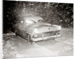 1950s Snow Covered Automobile Driving On Road In Deepening Winter Blizzard Snow by Anonymous