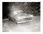 1950s Snow Covered Automobile Driving On Road In Deepening Winter Blizzard Snow by Anonymous