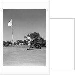 1950s Man Playing Golf Putting Golf Ball On Green To Flag And Cup Outdoor by Anonymous
