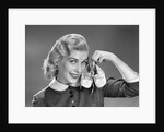 1950s 1960s Smiling Blond Woman Communicating That She Is Mother To Be By Holding Up A Pair Of Baby Shoes Looking At Camera by Anonymous